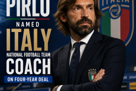 Andrea Pirlo smiling in a suit, posing for the camera at a press conference as Italy national football team coach.
