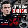 Joey Barton in a police custody setting, looking serious and wearing a dark jacket.