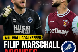 Millwall goalkeeper Filip Marschall gestures angrily accusing West Ham's Taty Castellanos of spitting during a match.