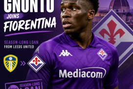 Wilfried Gnonto wearing Fiorentina jersey, smiling and holding a football on the field during a match.